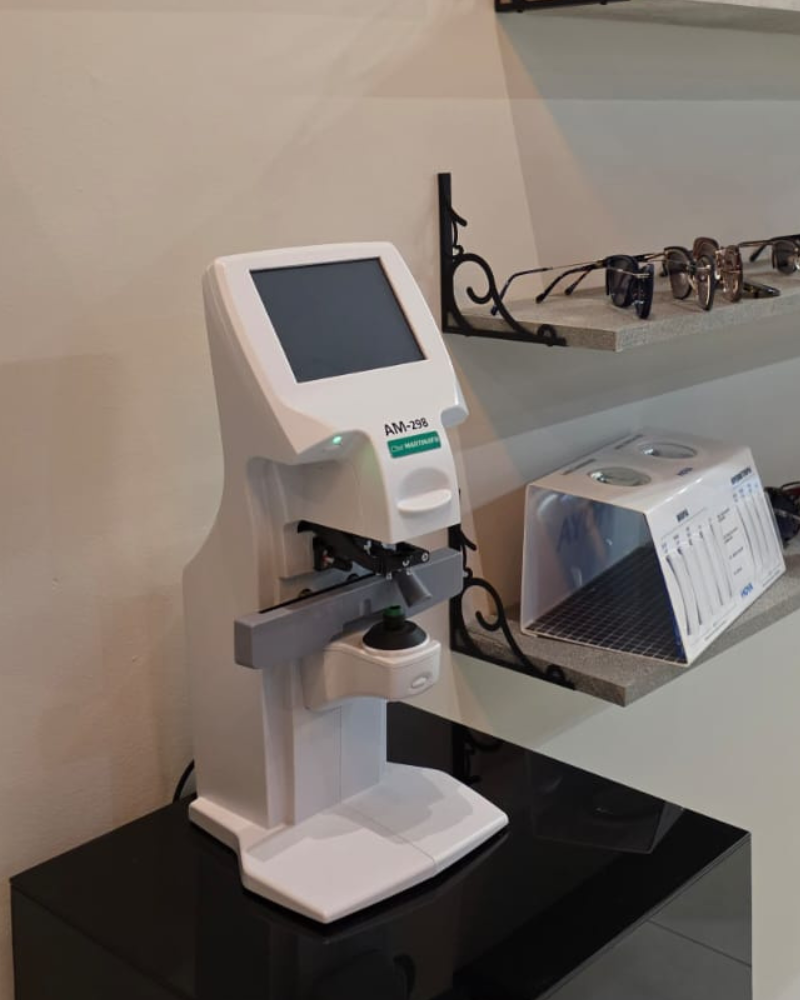 Lensômetro digital em uso no Atelier do Óculos — técnico óptico verificando lentes com equipamento de medição