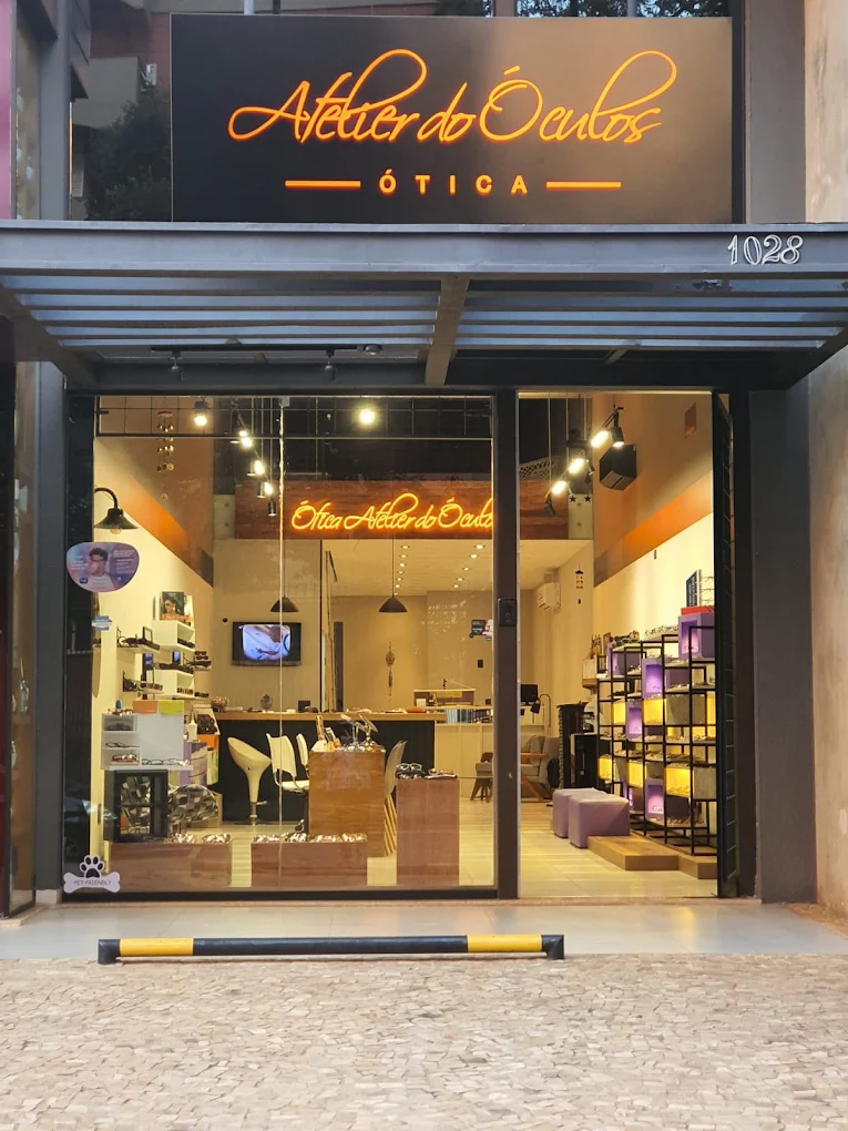 Fachada da ótica Atelier do Óculos no Centro de Londrina, com letreiro neon laranja, número 1028